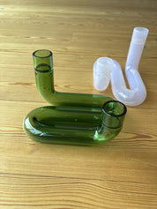 zwei Kerzenhalte auf Holzboden, einer grün, einer rosa