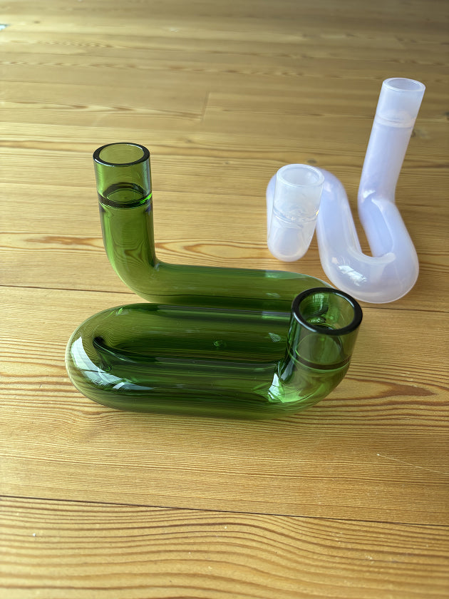 zwei Kerzenhalte auf Holzboden, einer grün, einer rosa